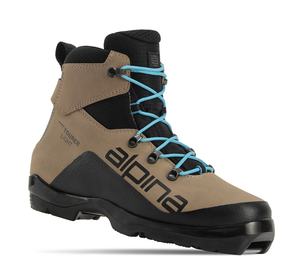 Alpina Tourer Light cross-country ski boot designed for light touring. The mid-cut boot features a beige and black upper, light blue laces, and a supportive padded ankle collar. Lightweight and water-resistant, it offers flexibility and comfort for recreational use on groomed or light off-track terrain.