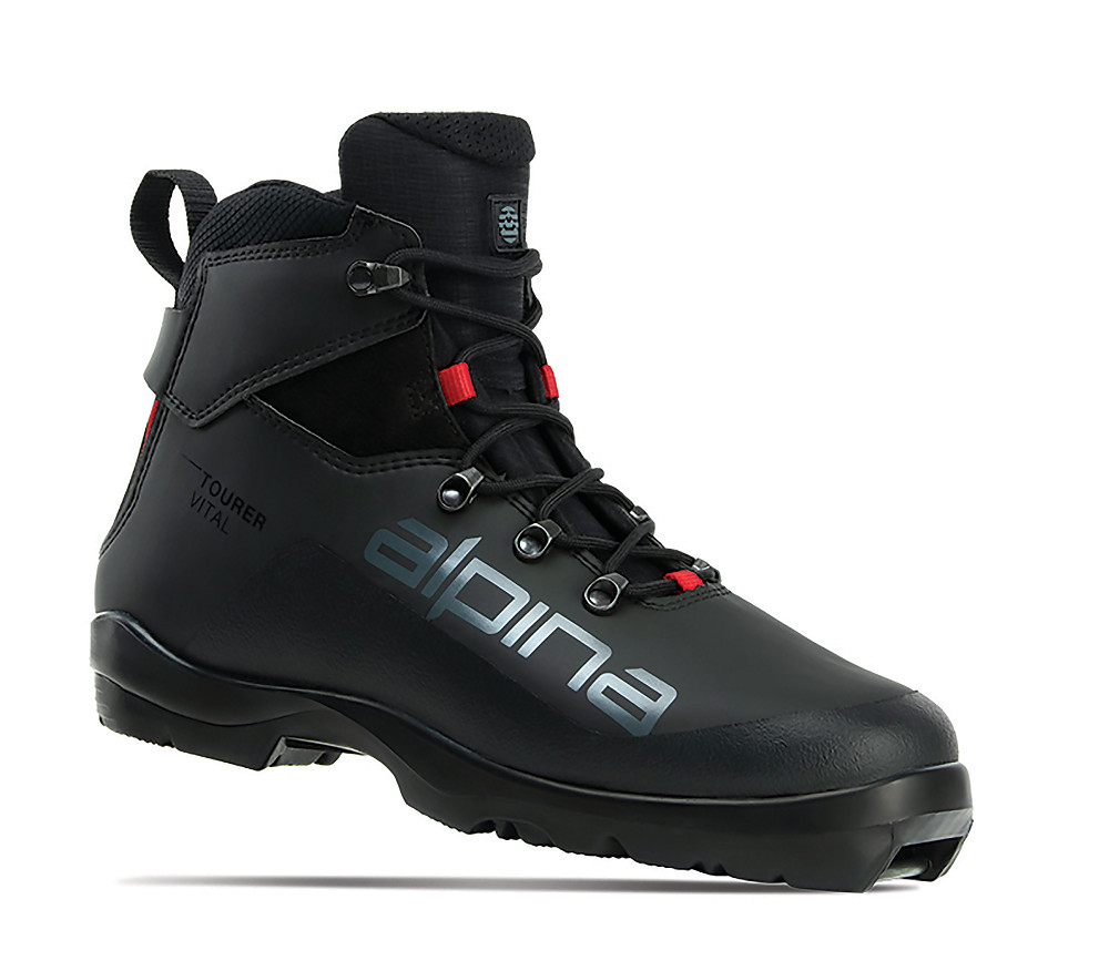 Alpina Tourer Vital ski boot, designed for cross-country touring. The mid-height black boot features a sleek design with soft ankle support, red accent eyelets, and a prominent Alpina logo on the side. Built for comfort and stability on groomed trails, it combines water-resistant materials and light insulation for cold-weather performance.