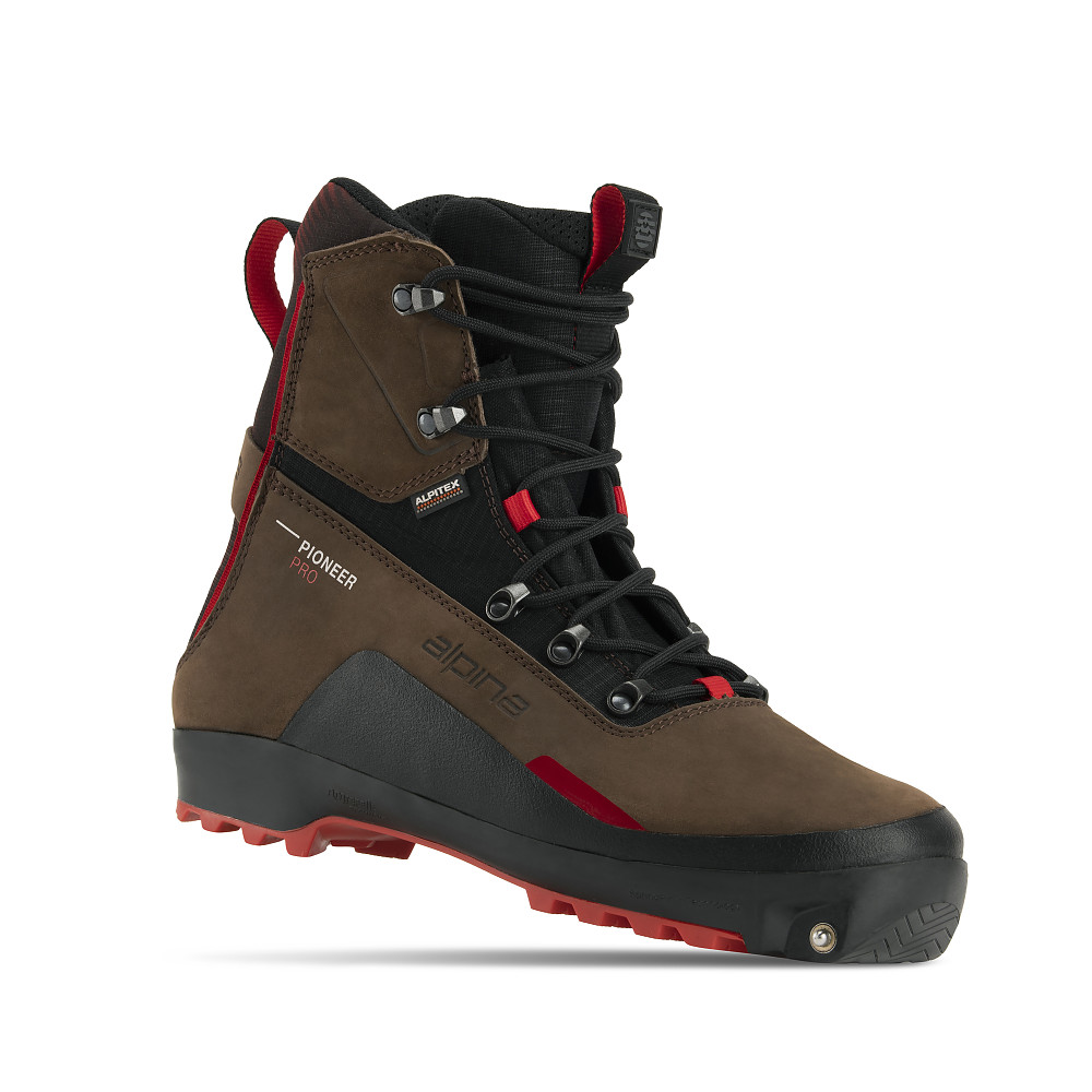Alpina Pioneer Pro backcountry ski boot designed for off-track skiing in harsh winter conditions. The high-cut brown and black boot features a red outsole, metal lace hooks, and ALPITEX waterproof membrane. Reinforced for ankle support and wip on, goiders comfort.