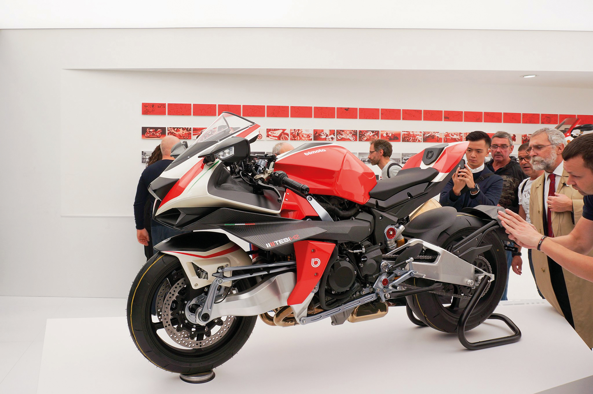 A photo of the Bimota stand at Eicma show 2019 in Milano, showing the newly presented Bimota Tesi H2 motorcycle on a tall white pedestal.