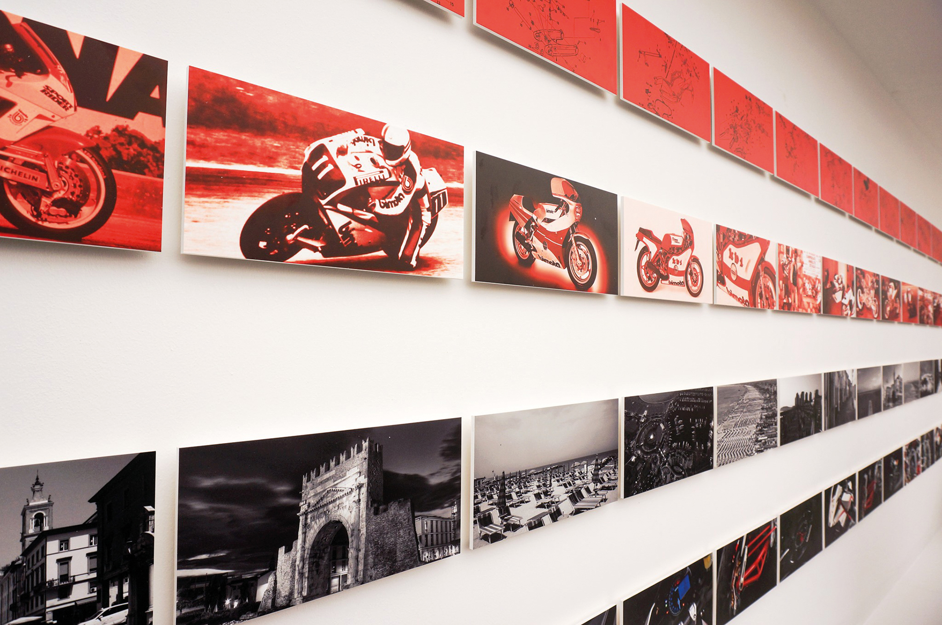 A photo of the Bimota stand at Eicma show 2019 in Milano, showing the wall with small photos, describing the Bimota heritage and technical knowledge.