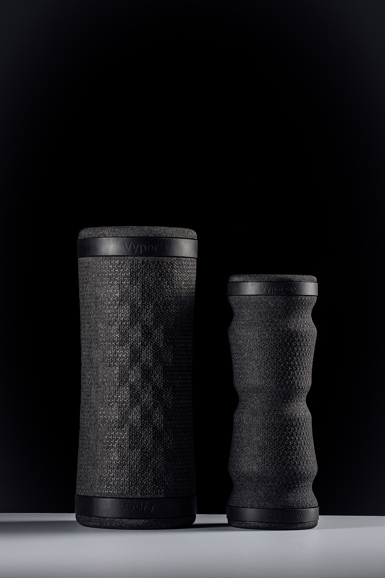 Photo of the Hyperice Vyper 3 and Vyper Go recovery massage foam rollers side by side, on black background.
