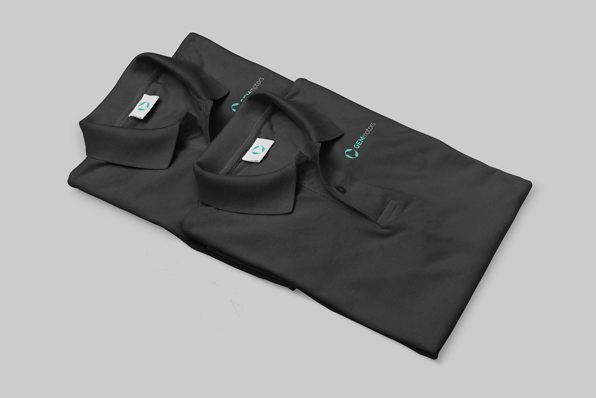 Branded black polo shirts for GEM Motors featuring the company logo embroidered on the chest and labeled tags, reflecting a professional and unified corporate identity.
